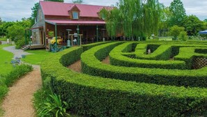 A building with a red roof and a garden with a hedge maze. - Bay House Motel (Bateau Bay)