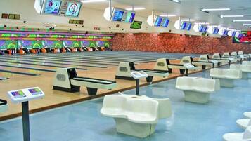 Une salle de bowling dotée de nombreuses pistes, de quilles et d’une rangée de sièges blancs.