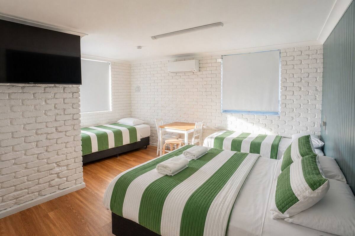 A room with two beds, a small table, and a TV.
