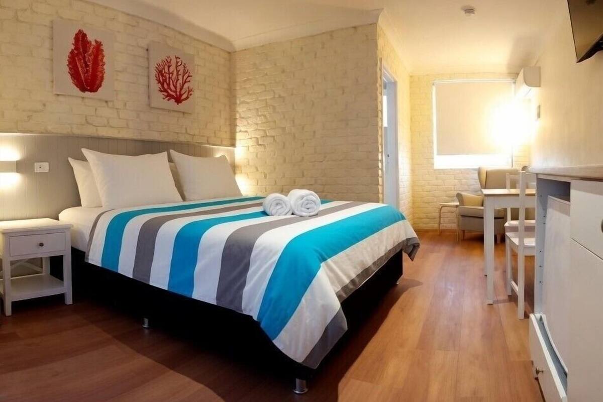 A bedroom with a bed, bedside tables, a desk, and a chair.