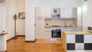 Eine moderne Küche mit weißen Schränken, einem Gasherd, einem Backofen und einer Mikrowelle.