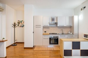 Une cuisine moderne avec des meubles blancs, une cuisinière à gaz, un four et un four à micro-ondes.