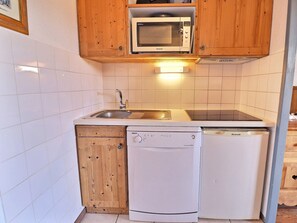 Una cocina compacta equipada con microondas, lavaplatos y fregadero.