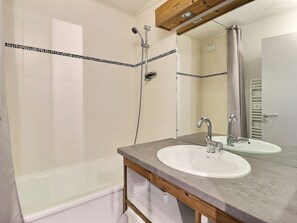 A bathroom with a bathtub, two sinks, a shower, and a wooden vanity. - Comfortable 2 Rooms + Cabin, Ski-In/Ski-Out, 5/6 People (La Tania)