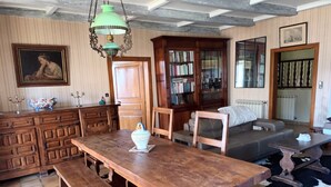 A traditional room with a wooden table, benches, a bookshelf, a sofa, and a radiator.