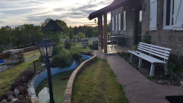 A patio area with a stone bench, a small pond, and a stone wall.