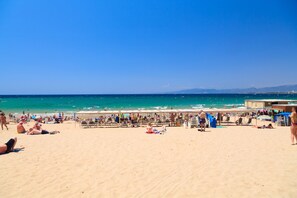 A beach with people sunbathing and swimming, tents, and beach chairs. - UHC PLAYAMERO FAMILY COMPLEX 309 (Salou)