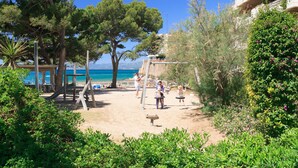 Une zone de plage avec une terrasse en bois, une balançoire et une vue sur la mer.