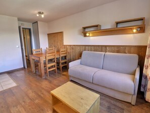 Un salon comprenant un canapé, une table à manger en bois, des chaises et une petite table basse en bois.