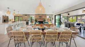 A spacious dining area with a large island, wicker chairs, and a central table set for a meal.