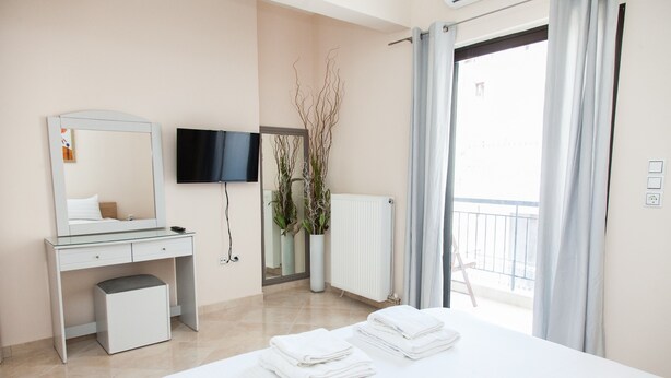 Een moderne hotelkamer met een bed, een bureau, een televisie en een balkon met gordijnen.