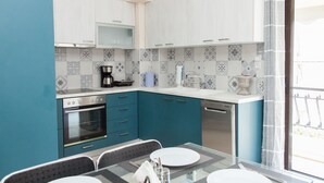Een moderne keuken met blauwe kastjes, een glazen eettafel en uitzicht op de omgeving.