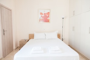 A neatly made bed with white linens, a bedside table with a lamp, and a wardrobe with sliding doors.