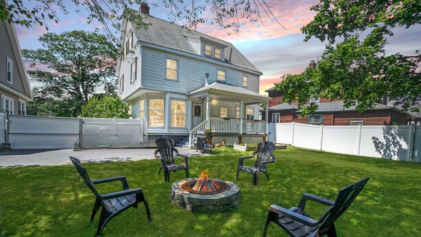 A two-story house with a front porch, a fire pit in the backyard, and a covered patio area. - Dancing Queen by Bayley Vacation Rentals (Old Orchard Beach)