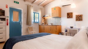 Ein Schlafzimmer mit Bett, Schreibtisch, einer Küchenzeile und einem Badezimmer.