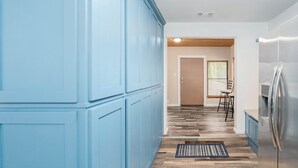 Une cuisine avec des armoires bleues, un plancher en bois et un réfrigérateur en acier inoxydable.