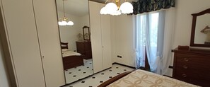 A bedroom with a bed, a dresser, a mirror, a wardrobe, and a chandelier.