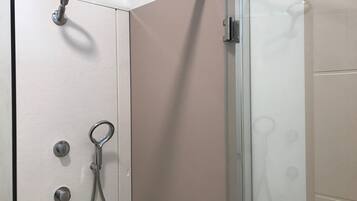 Una ducha con paredes de vidrio, puerta corrediza, toallero y cabezal de ducha.