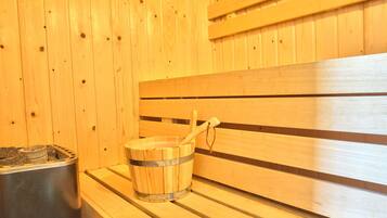 A wooden sauna bench with a bucket and a wooden mallet.
