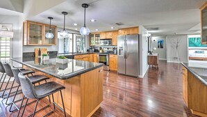 Una cocina moderna con armarios de madera, electrodomésticos de acero inoxidable y una isla central con taburetes de bar.