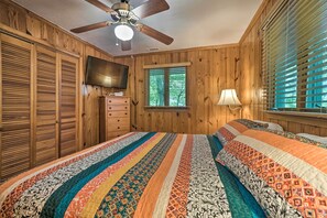 A bedroom with wooden paneling, a ceiling fan, a TV, a dresser, a window with blinds, and a patterned bedspread. - Serene Sky Valley Family Chalet w/ Fireplace (Sky Valley)