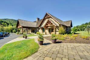 A stone building with a pitched roof and wooden beams, surrounded by a well-maintained lawn and potted plants. - Serene Sky Valley Family Chalet w/ Fireplace (Sky Valley)