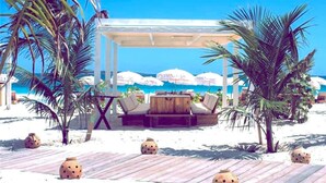 A beachside lounge with a wooden deck, palm trees, and a view of the ocean. - Front line unit 520 ft2 on 2nd floor facing ocean (Orient Bay)