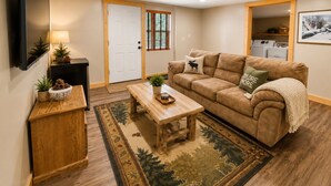 A living room with a sofa, coffee table, and a TV mounted on the wall.