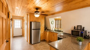 A kitchen with wooden cabinets, a stainless steel refrigerator, a microwave, and a stove.