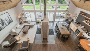 Um amplo loft com uma grande sala de jantar, cozinha e área de estar, com janelas amplas com vista para um jardim.