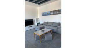 A modern living room with a grey sectional sofa, a flat-screen TV, a glass coffee table, and a painting on the wall. - Maison de Maître Gironde built in 1896 and fully restored (saint philippe d'aiguille)