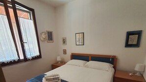 A bedroom with a bed, two bedside tables, a window with curtains, and wall decorations. - Sicicas, 300 meters from the sea, 5 minutes walk (Villasimius)