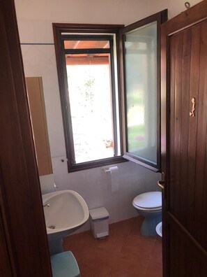 Een badkamer met een bad, toilet en een raam.