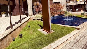 A modern building with a swimming pool, a covered outdoor area, and multiple flags. - Apart-Hotel Prinz (Joinville)