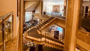 A spacious interior with a grand staircase, marble flooring, and a high ceiling. - Apart-Hotel Prinz (Joinville)