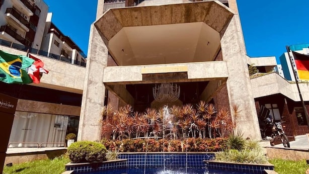 A high-rise building with a central courtyard featuring a fountain and a swimming pool. - Apart-Hotel Prinz (Joinville)