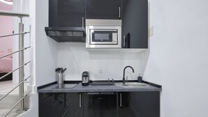 Una cucina compatta con forno a microonde integrato, macchina del caffè e lavandino.