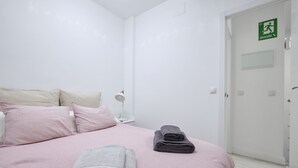 Una camera d'albergo con un letto, cuscini e asciugamani piegati.
