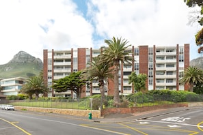 A multi-story building with balconies, surrounded by palm trees and a mountain in the background. - Sonnekus 5 (Cape Town)