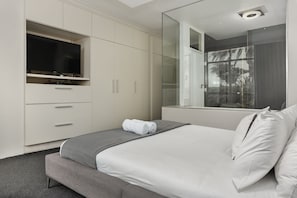 A modern hotel room with a bed, a TV on a shelf, a large window, and a wardrobe. - Sonnekus 5 (Cape Town)