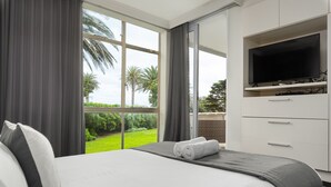 A hotel room with a bed, a TV, and a view of greenery outside. - Sonnekus 5 (Cape Town)