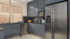 A modern kitchen with grey cabinets, stainless steel appliances, and a built-in microwave. - Sonnekus 5 (Cape Town)
