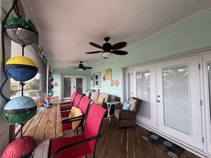 A covered patio with a wooden table and red chairs, a ceiling fan, and a 'Beach' sign on the wall. - Pool, tiki hut, easy ocean access canal, dock, prime location 30m to Key West (Cudjoe Key)