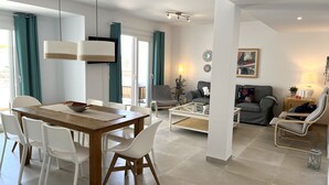 Een moderne woonkamer met een eethoek, een bank, een salontafel en een fauteuil.
