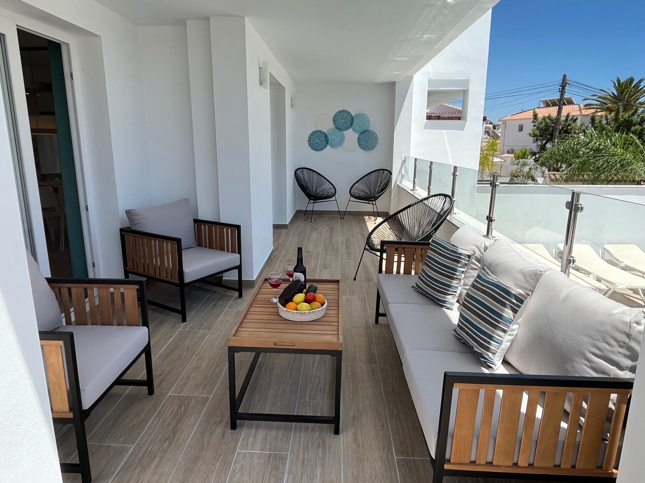 Un balcon avec une table en bois, deux canapés et deux chaises.