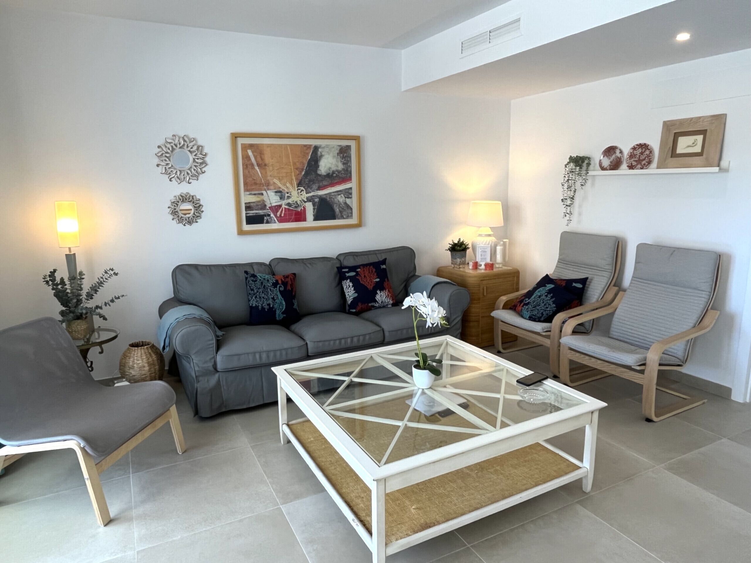Un salon moderne avec un canapé gris, une table basse blanche et une chaise en bois.