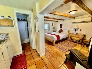 Un dormitorio con cama, cabecera de madera, mesita de noche, lámpara y ventana.