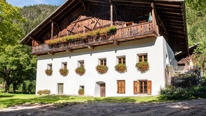 A traditional wooden building with a balcony, multiple windows, and flower boxes. - Apartment "Linde - Fiechterhof" with Shared Open Terrace, Garden & Wi-Fi (Sarentino)