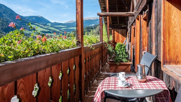 A wooden balcony with a table, chairs, and a view of mountains. - Apartment "Linde - Fiechterhof" with Shared Open Terrace, Garden & Wi-Fi (Sarentino)