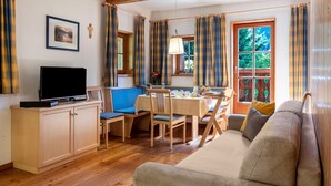 A living room with a sofa, a dining table with chairs, a television, and a window with curtains. - Apartment "Linde - Fiechterhof" with Shared Open Terrace, Garden & Wi-Fi (Sarentino)